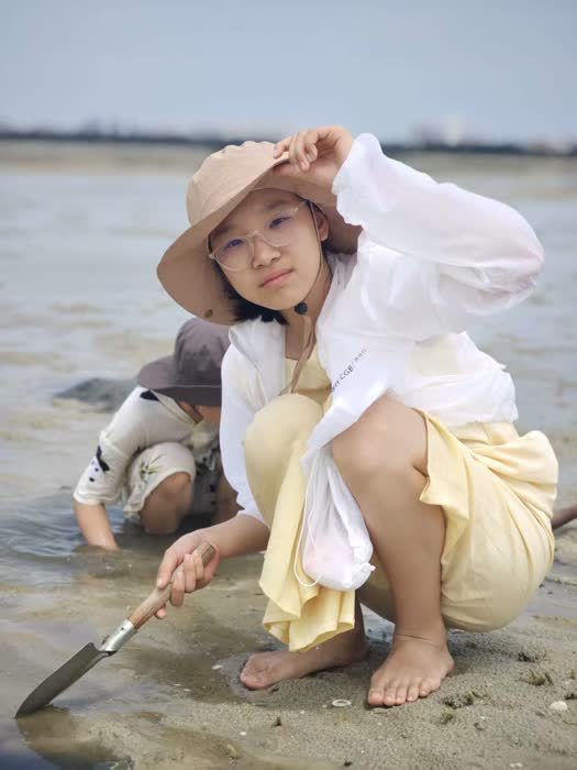 海滩边蹲下观察的照片